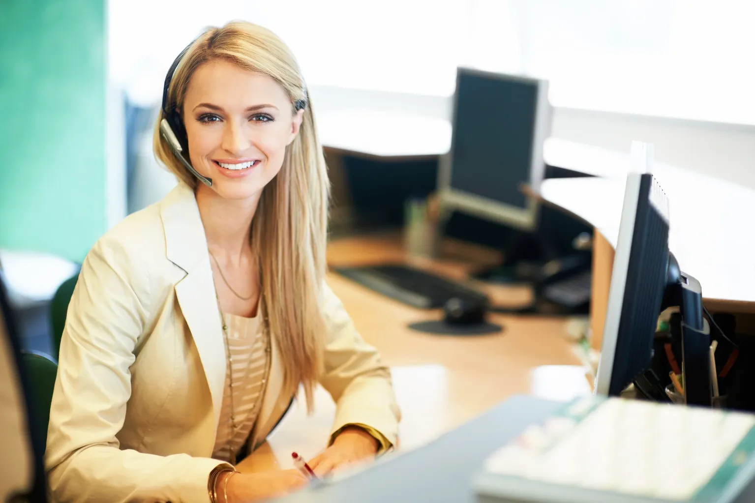 Smiling businesswoman with headset at desk Telehealth